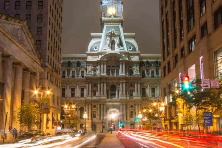 Night view of a historic building with light trails on the street in front.