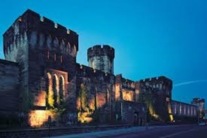 Illuminated stone castle exterior at dusk with blue sky background.