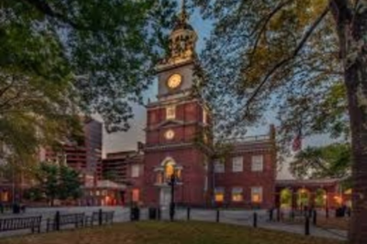 Historic brick building with clock tower, surrounded by trees.