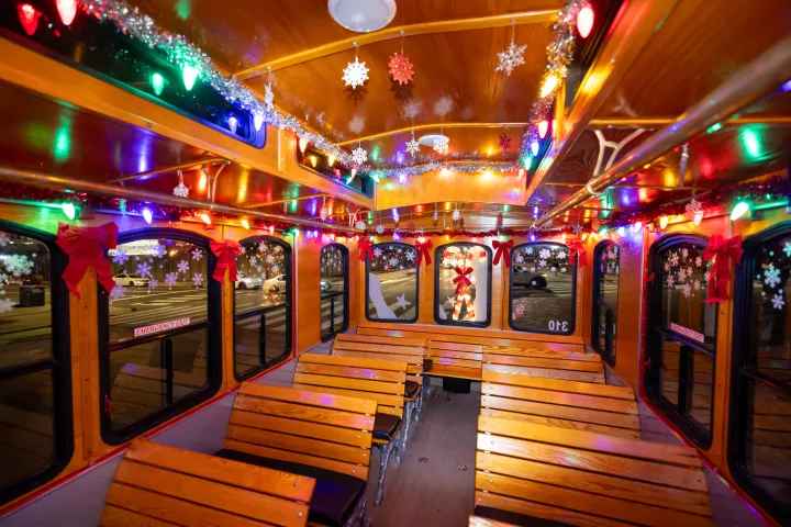 Interior of a trolley decorated with colorful Christmas lights and ornaments.