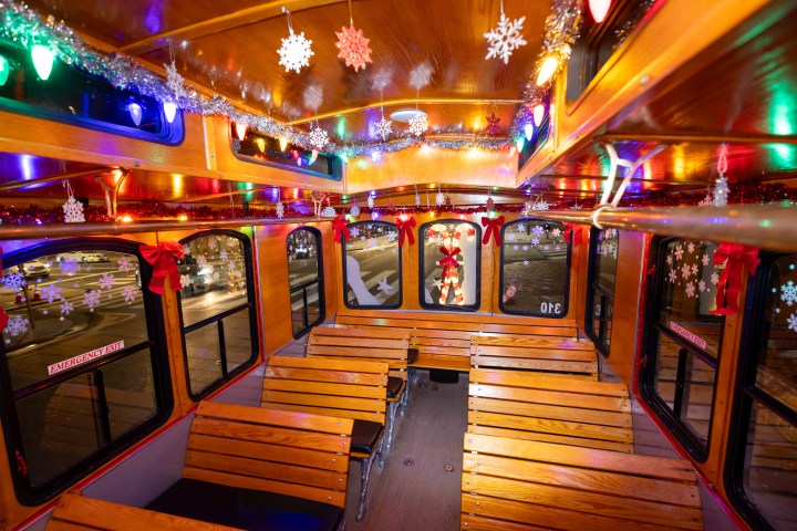 Festively decorated bus interior with lights, snowflakes, and ribbons.