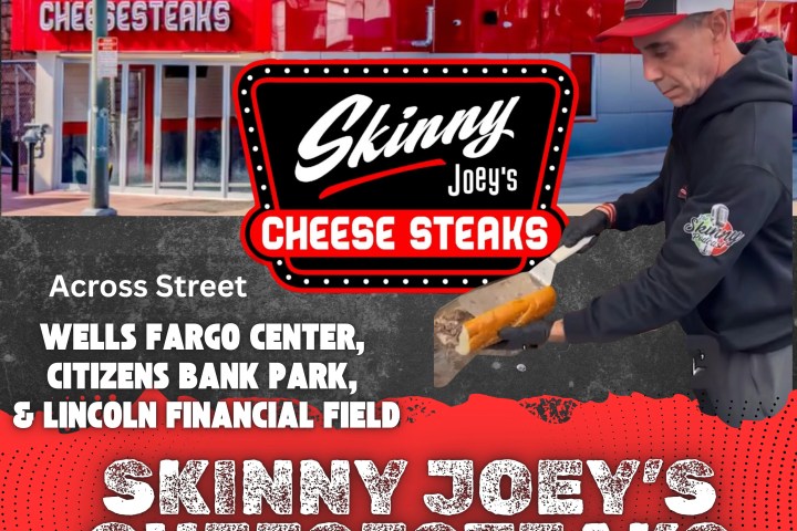 Building with 'Skinny Joey's Cheesesteaks' signs and man preparing food outside.