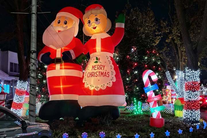 Inflatable Santa and Mrs. Claus with Christmas lights and candy canes in a festive outdoor display at night.