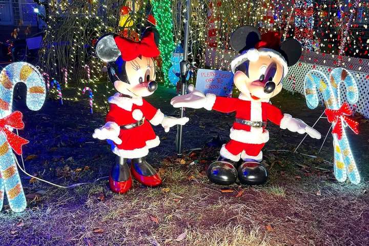 Festive figures of cartoon mice in Santa outfits amid colorful Christmas decorations and lights.